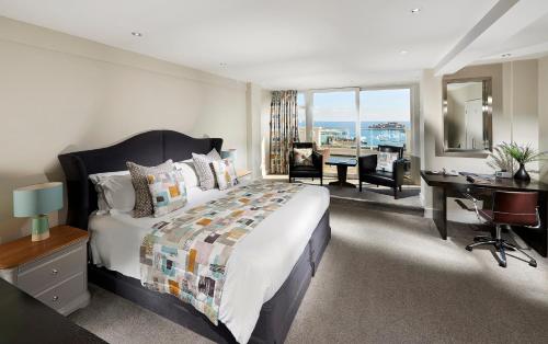 a bedroom with a large bed and a desk and a room with a view at La Fregate Hotel in St Peter Port