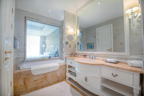 een badkamer met een bad, een wastafel en een spiegel bij Huachen International Hotel in Chongqing