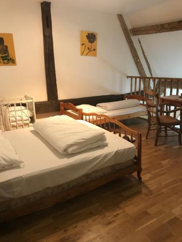 2 camas en una habitación con suelo y sillas de madera en La Huberdière, en Fondettes