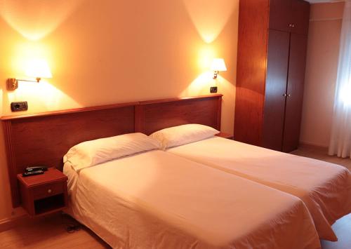 a bedroom with a large white bed with two pillows at Hotel Maycar in A Coruña