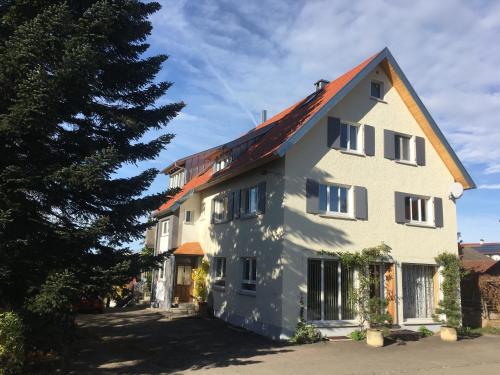 uma grande casa branca com uma árvore em frente em Bei uns im Allgäu em Bad Wurzach