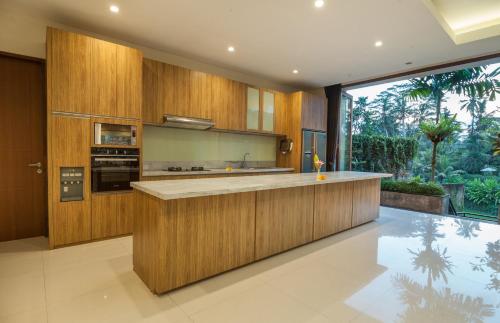 a large kitchen with wooden cabinets and a large window at River Sakti Ubud by Prasi in Ubud