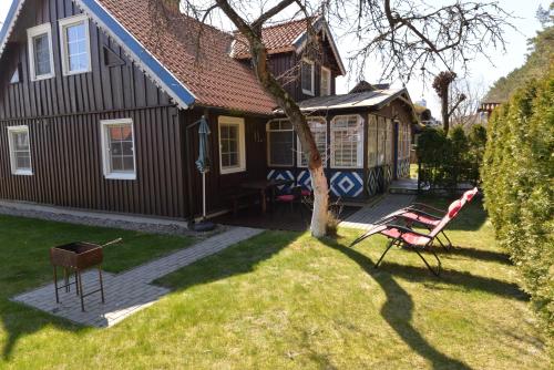 a house with a deck and a chair in the yard at Preiloje pas Žilviną in Neringa