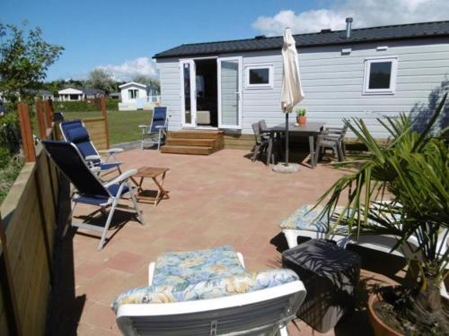 a patio with chairs and an umbrella and a house at Chalet Joleen IJmuiden aan zee, vlakbij het strand in IJmuiden