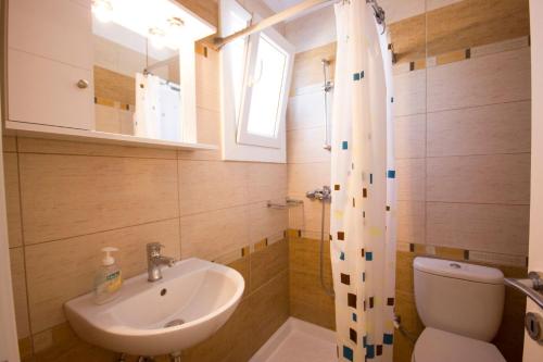 a bathroom with a sink and a toilet and a window at Sahas Apartments in Mikonos