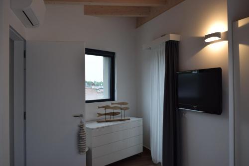 a room with a tv and a dresser and a window at Villa Alcova in Caorle