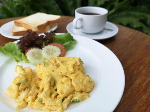 a plate of food with eggs and a cup of coffee at Bansabai Hostelling International in Bangkok