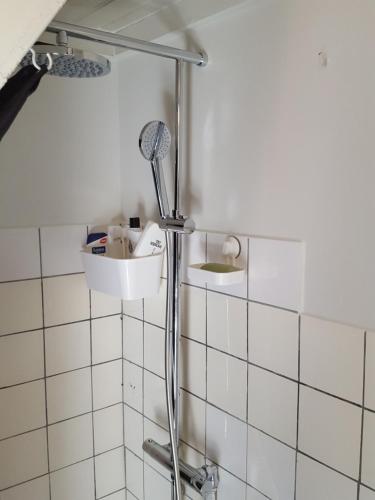 W wyłożonej białymi kafelkami łazience znajduje się prysznic. w obiekcie Cosy Farmhouse Single bedroom w mieście Stege