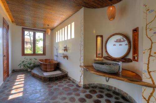 a bathroom with a tub and a sink and a mirror at Can Tho Ecolodge in Can Tho