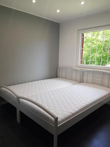 a white bed in a room with a window at Picurka Apartman in Siófok