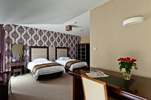 een hotelkamer met 2 bedden en een bureau bij Hotel Borowina in Konstancin-Jeziorna