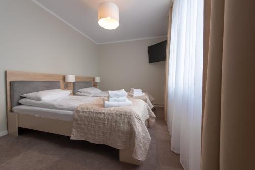 a bedroom with two beds with white sheets and towels at Biały Gościniec in Ciechanów