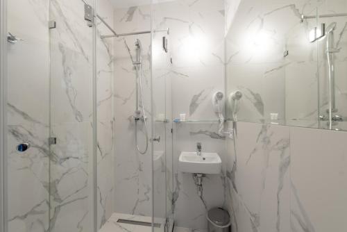 a white bathroom with a shower and a sink at Biały Gościniec in Ciechanów
