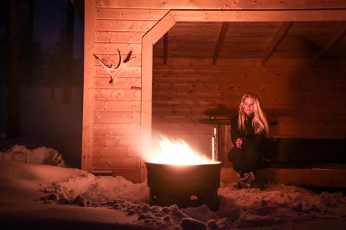 a woman sitting in a cabin next to a fire at Åsarna Skicenter in Åsarne
