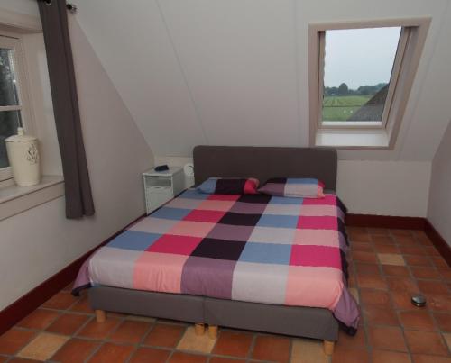 a bedroom with a bed with a striped comforter and a window at NeyenGreve in Bennekom