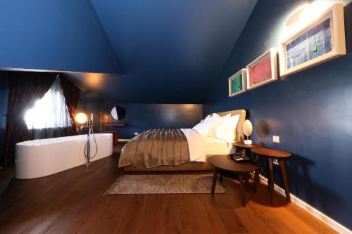 a bedroom with blue walls and a bed and a tub at Boutique Hotel Boškinac in Novalja