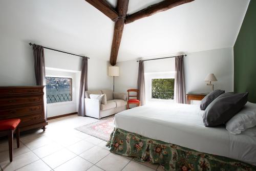 a bedroom with a bed and a couch and windows at Hotel Orso Bruno in Carate Urio