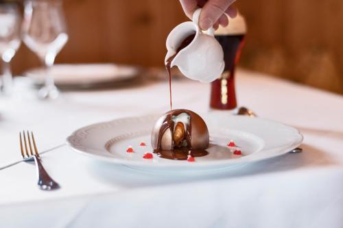 a person drizzling sauce onto a chocolate dessert on a plate at Schlosswirt Forst in Lagundo