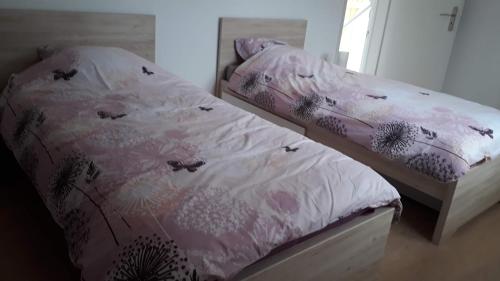 a bed with a pink comforter with butterflies on it at Ferme en pleine campagne in Castelsagrat