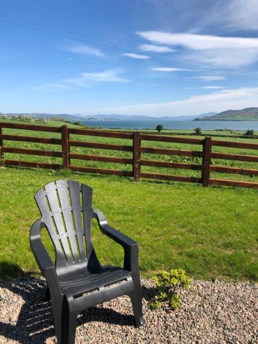 a chair sitting in the grass near a fence at Oakwell holiday village in Ramelton