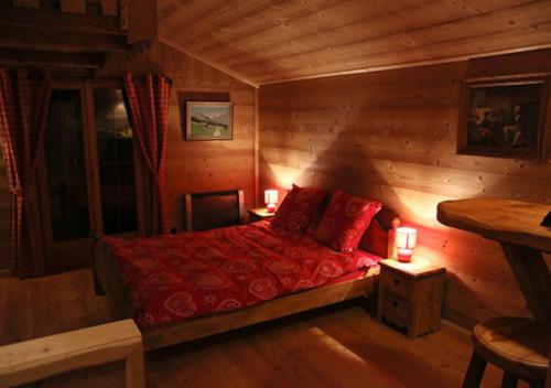 una camera con letto rosso in una baita di tronchi di Au Petit Gîte Les Paccots a Châtel-Saint-Denis