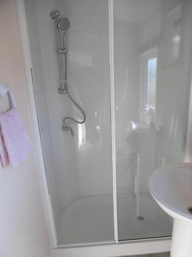 a white bathroom with a shower and a sink at Chalet Joleen IJmuiden aan zee, vlakbij het strand in IJmuiden
