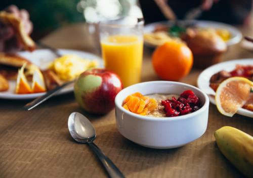 a bowl of cereal with fruit and a glass of orange juice at Au Petit Gîte Les Paccots in Châtel-Saint-Denis
