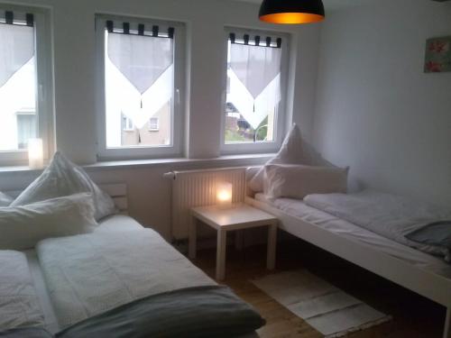 Habitación con 2 camas, mesa y ventanas. en Ferienwohnung Konrad - nahe Chemnitz, en Limbach - Oberfrohna