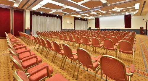 an empty lecture hall with red chairs and a screen at Best Western Classic Hotel in Reggio Emilia