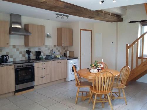 une cuisine avec une table et des chaises en bois, une table et une cuisinière dans l'établissement Le Grenier, La Vieille Ferme, à Ruffiac