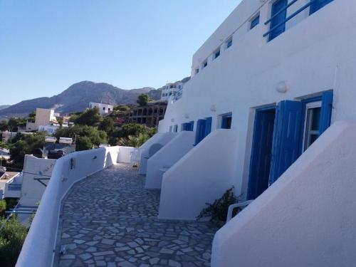 a walkway with white buildings and blue doors at Ariadne Studios in Kalymnos