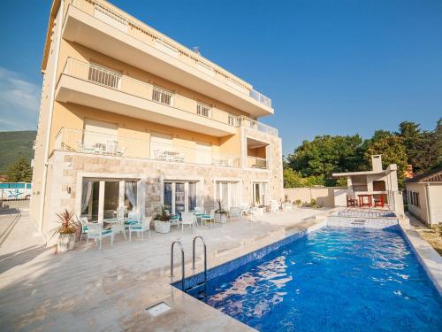 a building with a swimming pool next to a house at Sea Point II Apart hotel Tivat in Tivat