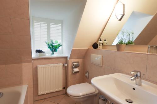 ein Badezimmer mit einem Waschbecken, einem WC und einem Spiegel in der Unterkunft Meinsbur Boutique Hotel in Bendestorf