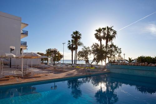 une piscine bordée de palmiers et un hôtel dans l'établissement BLUESEA Anba Romaní, à Cala Millor