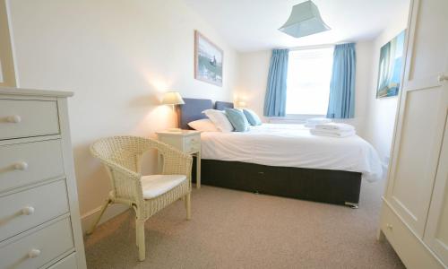 a bedroom with a bed and a chair and a window at Cloudbreak Braunton, Sleeps 8 - Hot Tub hire - Dog Friendly in Braunton
