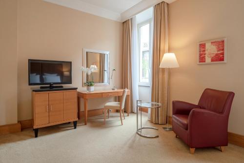 a living room with a television and a chair and a desk at Hotel Capo d´África – Colosseo in Rome