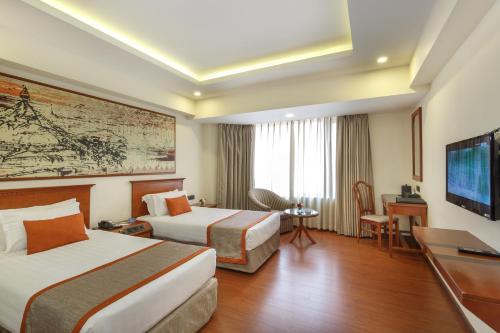 a hotel room with two beds and a flat screen tv at Royal Singi Hotel in Kathmandu