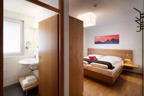 Schlafzimmer mit einem Bett, einem Waschbecken und einem Spiegel in der Unterkunft AlpinLodges Matrei in Matrei in Osttirol