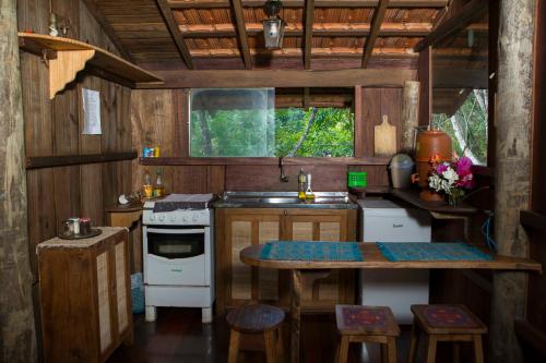 uma pequena cozinha com uma mesa e um fogão em Chalé Candeia no Matutu em Aiuruoca