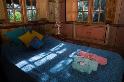 a bedroom with a blue bed with the sun shining on it at Chalé Candeia no Matutu in Aiuruoca