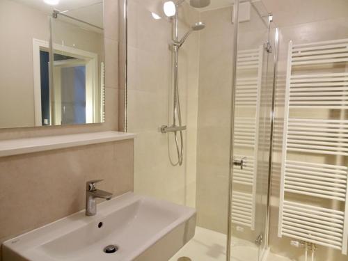 een badkamer met een wastafel en een douche met een spiegel bij Marschküken in Wrixum