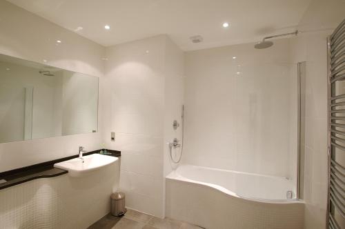 a white bathroom with a tub and a sink at La Fregate Hotel in St Peter Port
