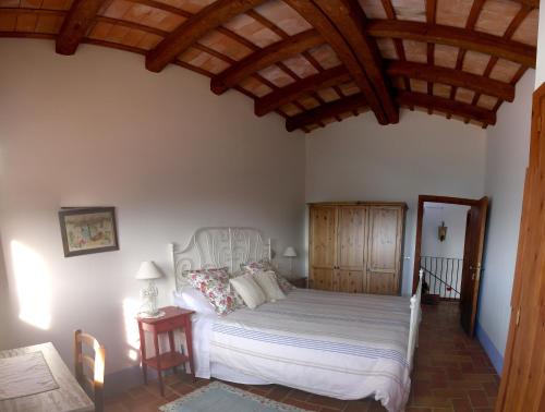 a bedroom with a white bed with a wooden ceiling at Mas del Salin in Cornudella