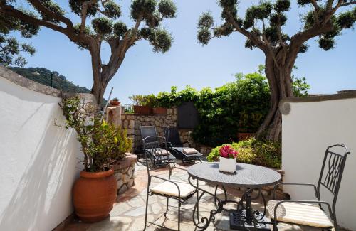 a patio with a table and chairs and trees at Sina Flora in Capri