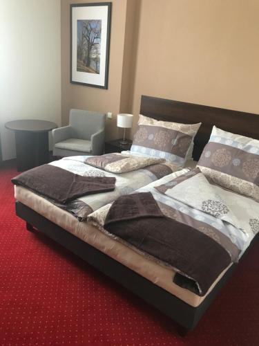 ein Schlafzimmer mit einem großen Bett und einem Stuhl in der Unterkunft Wellness hotel Harmonie Třeboň in Třeboň