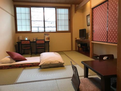 a room with a bed and a table and a window at Ryokan Sawaya Honten in Kyoto