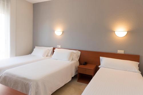 
a hotel room with two beds and two lamps at Hotel El Palmeral in Benidorm
