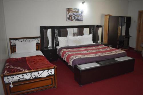 a bedroom with two beds and a ottoman in it at Tulip guesthouse in Islamabad
