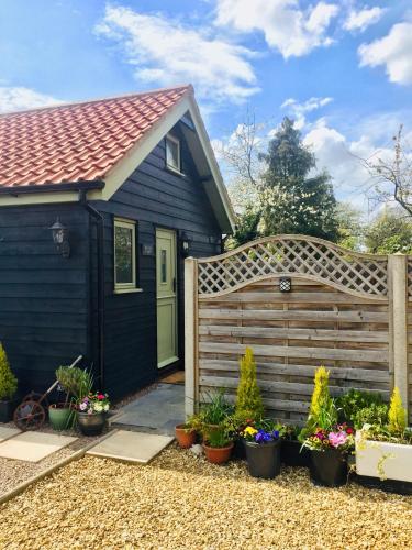 a house with a wooden fence and some plants at Saving Grace with private hot tub in Bawdeswell