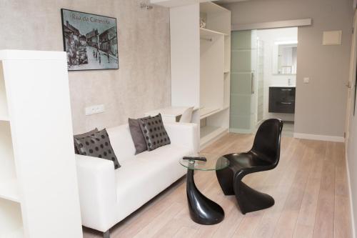a living room with a white couch and a black chair at Hostal Kukia in Noya